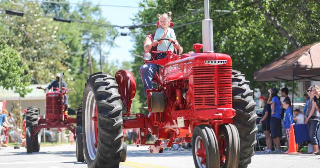 Girl waves from tractor in the Bostwick Cotton Gin Festival's tractor parade.