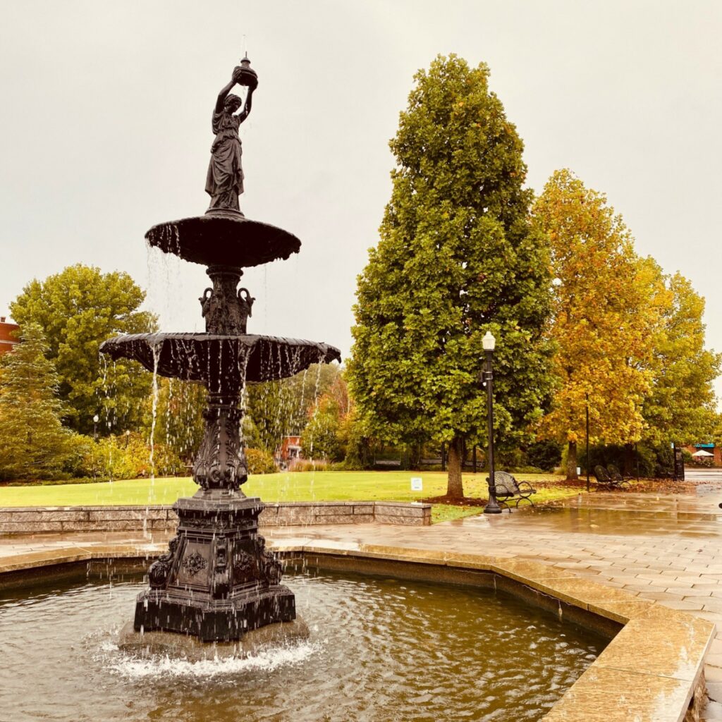 "Cooke Fountain in Town Park with autumn leaves on the trees in the background."