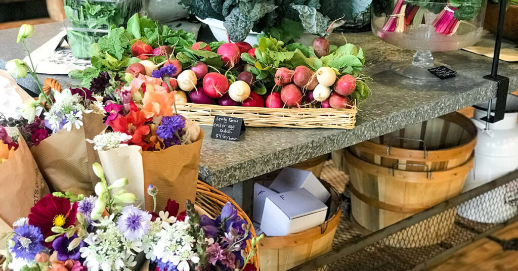 Flowers and local farm-to-table produce for sale displayed at Community Roots Market in Madison, GA