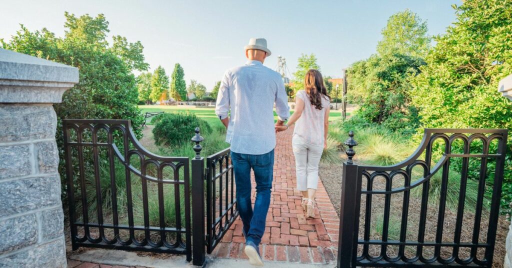 Couple on summer vacation holding hands while walking in Town Park.