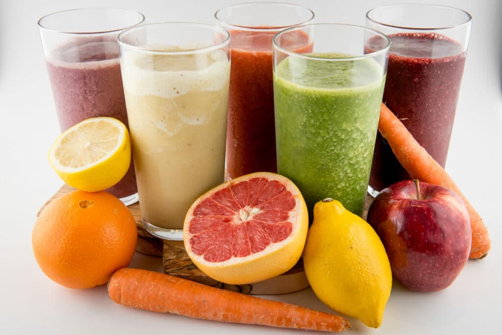 "Five smoothie options from Farmview surrounded by fruit and vegetables."