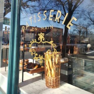 Store window of Patisserie on Main with view of baguettes.