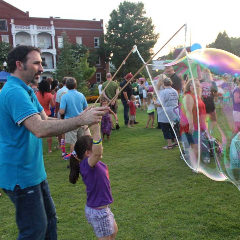 Father and daughter make giant bubbles at the Firefly Festival Kids' Night