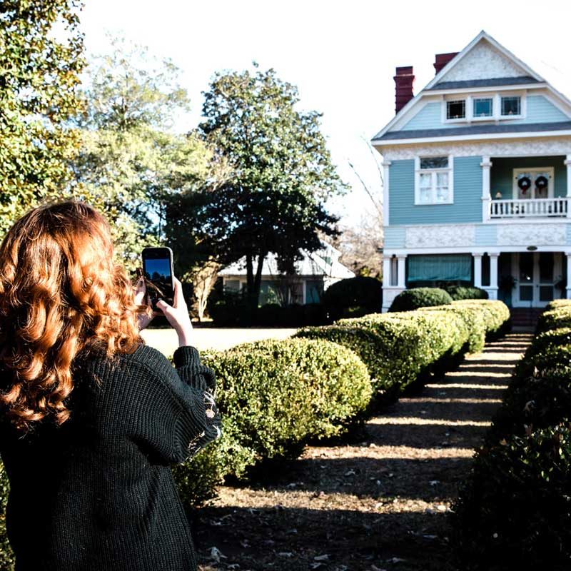 Woman photographs a house in Madison, Georgia's Historic Distri